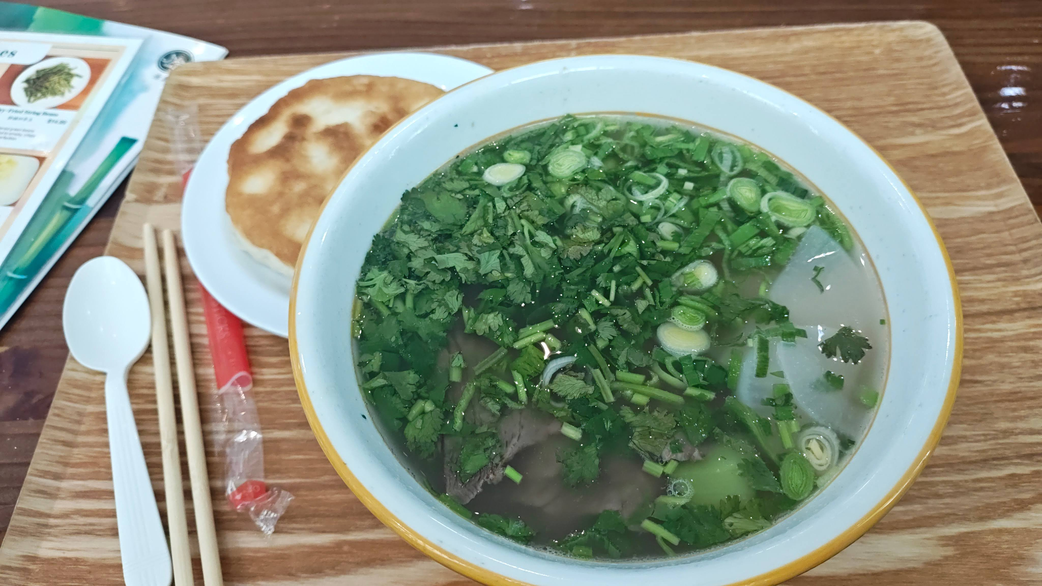 洒满香菜的兰州牛肉面和一个肉夹馍